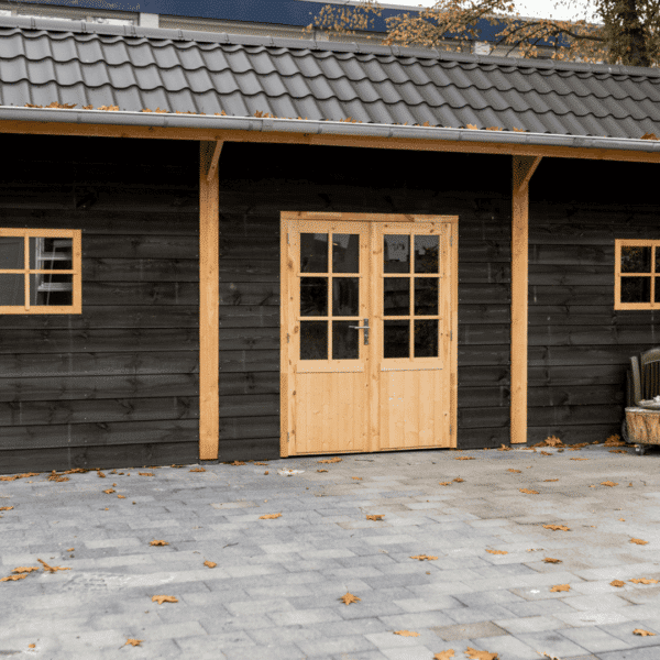 Douglas kapschuur met zwarte houten wanden, dubbele deur en bestrating in de tuin