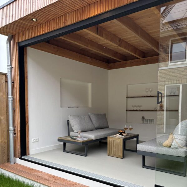 Tuinkamer onder een Douglas overkapping met glazen schuifwand en zitgedeelte